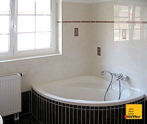 Ein Badezimmer mit geschwungener Badewanne und Fenster