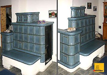 Eine Katze sitzt auf einer Bank vor einem Kamin.