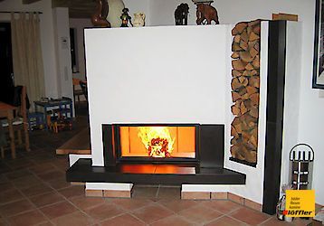 Ein Wohnzimmer mit Kamin und einem Holzstapel.