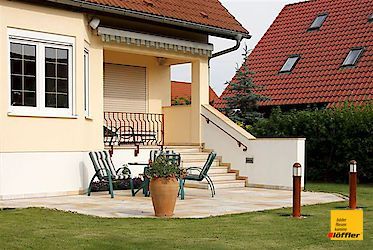 Ein Haus mit einer Terrasse und Stühlen davor