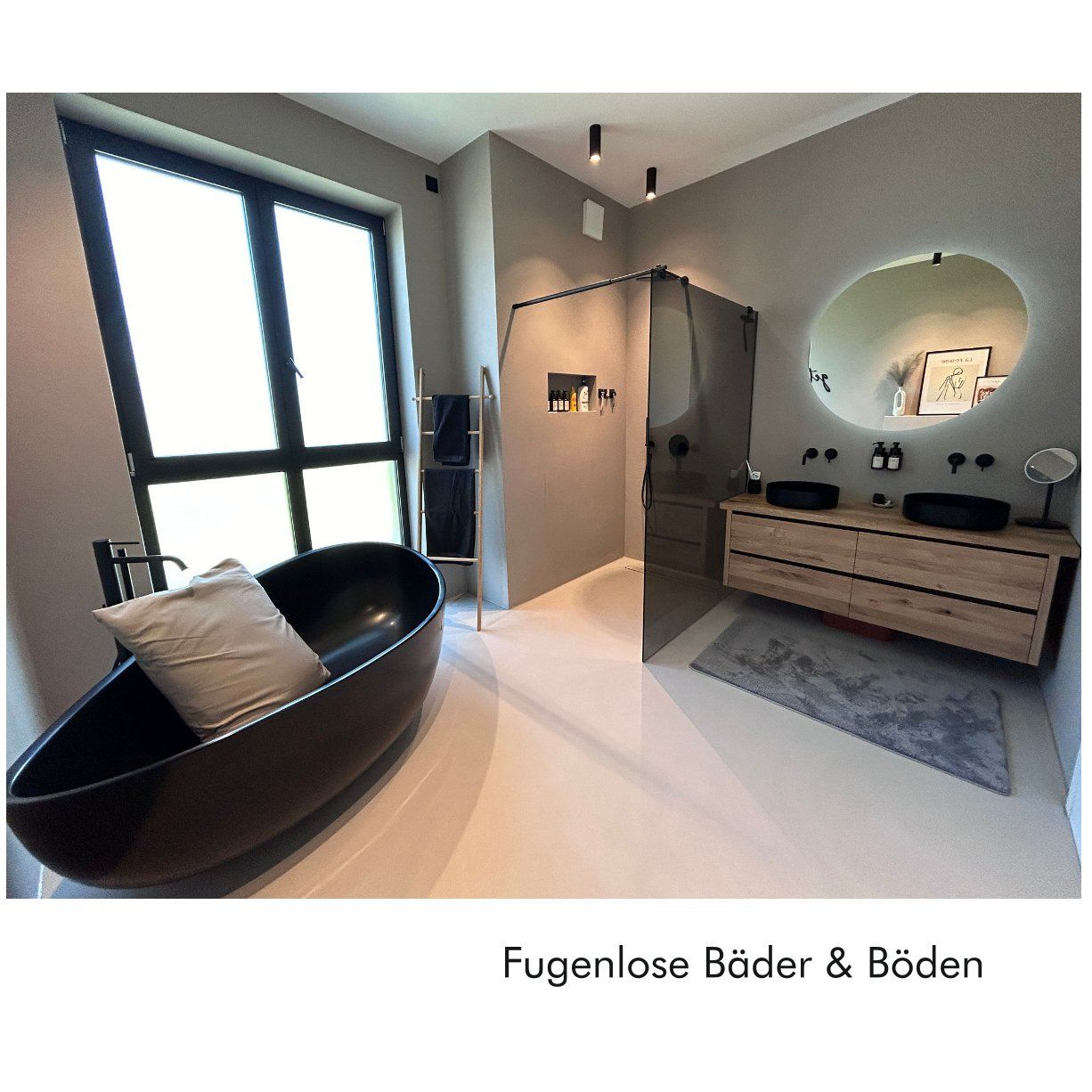 Saniertes, fugenloses Badezimmer mit frei stehender schwarzer Badewanne, ebenerdiger Dusche mit einer getönten Scheibe