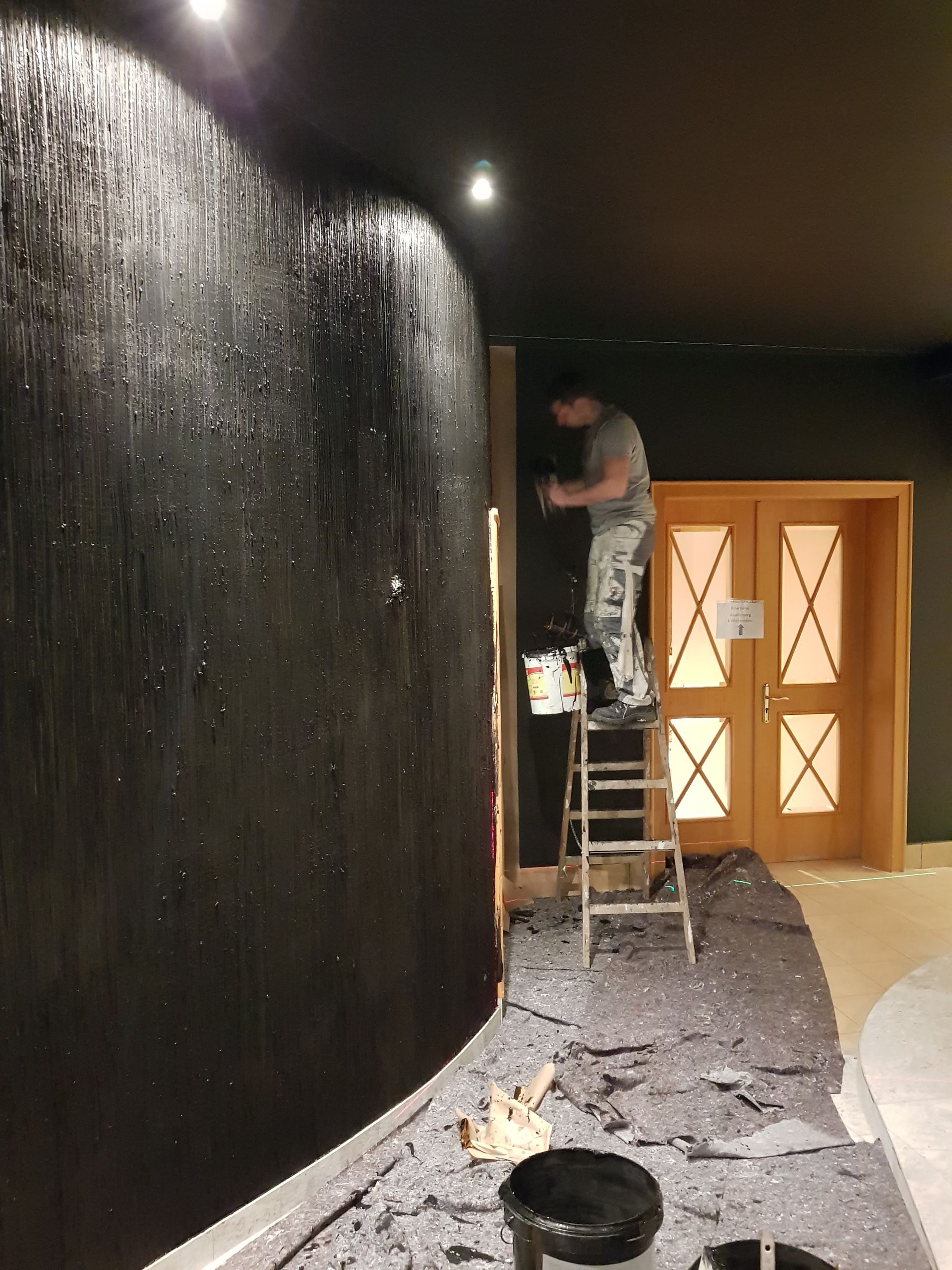 Maler beim Fertigen einer schwarzen Wand mit Strukturen