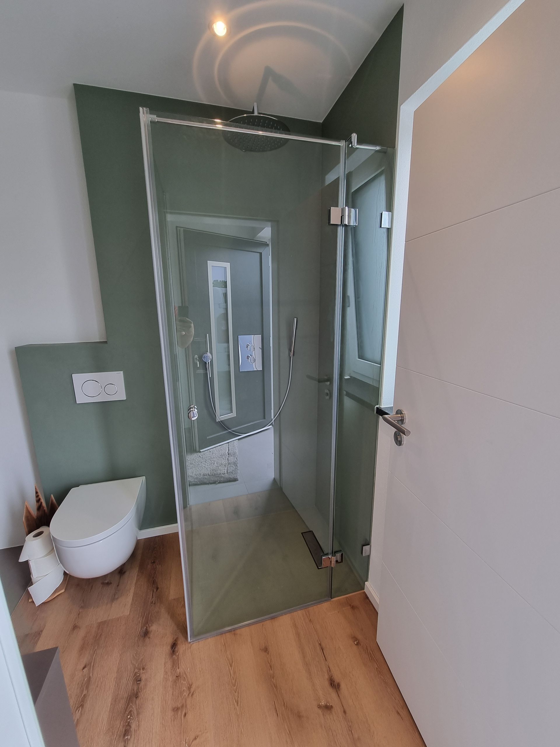 Kleines weißes Badezimmer mit mintgrünen Duschfliesen und Holzboden