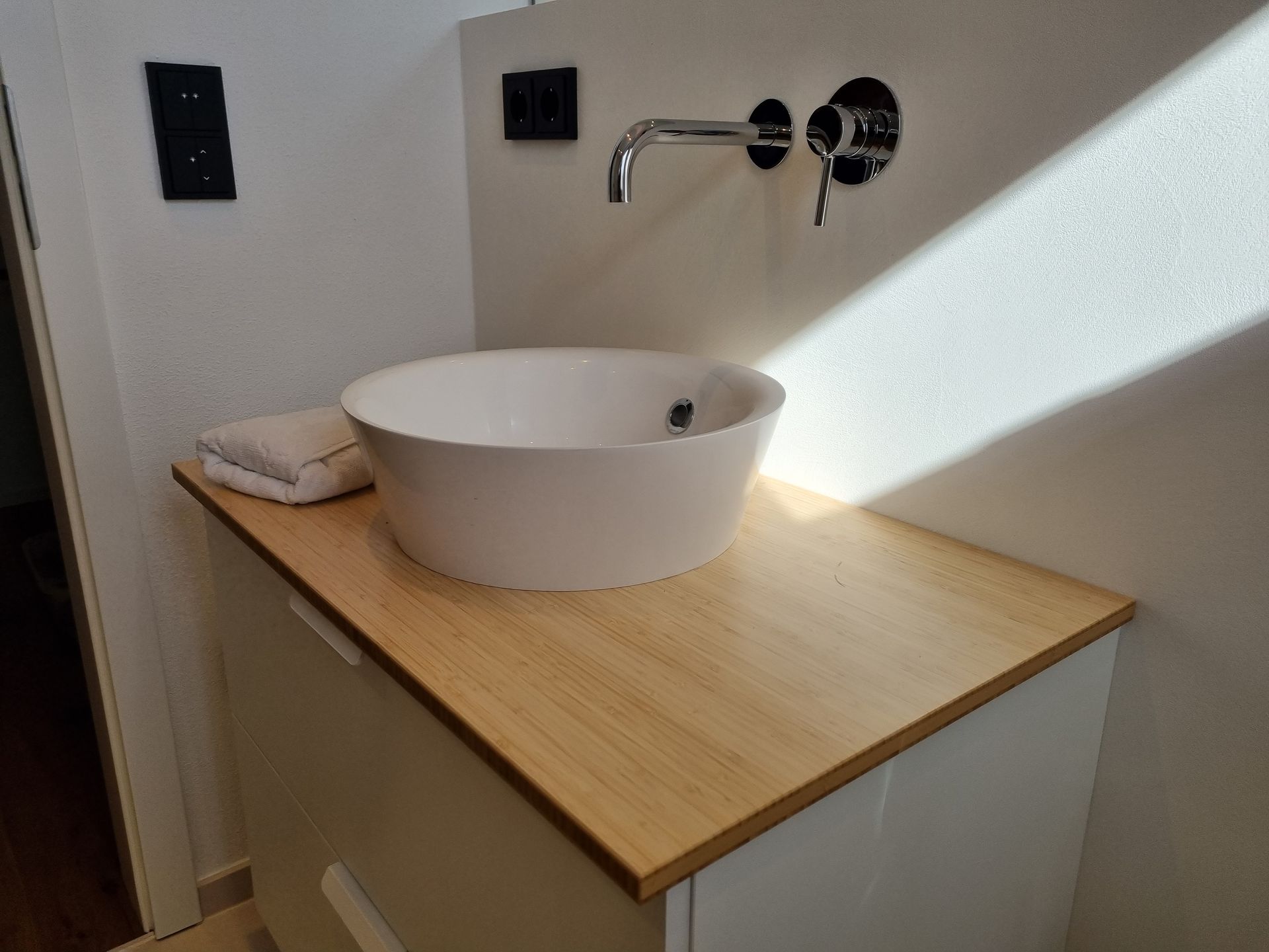 Rundes, weißes Waschbecken auf einem Holzschrank