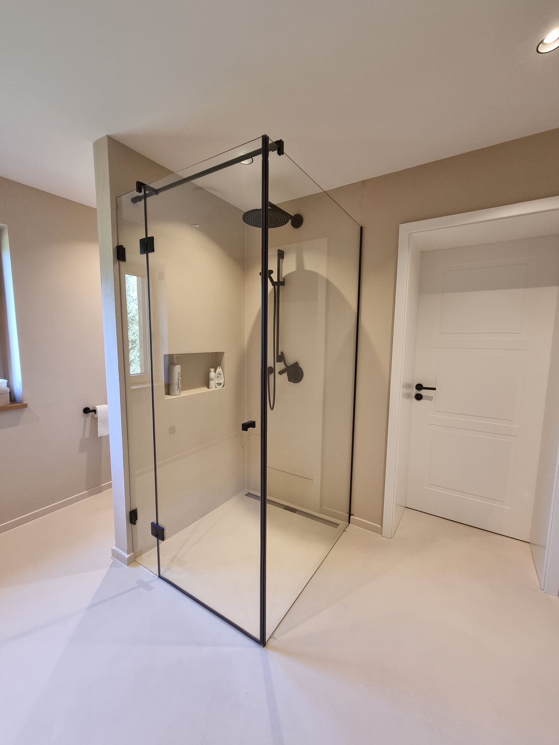 Links von der Trennwand eine Toilette, rechts davon eine ebenerdige Dusche mit in der Wand eingelassenem Regal