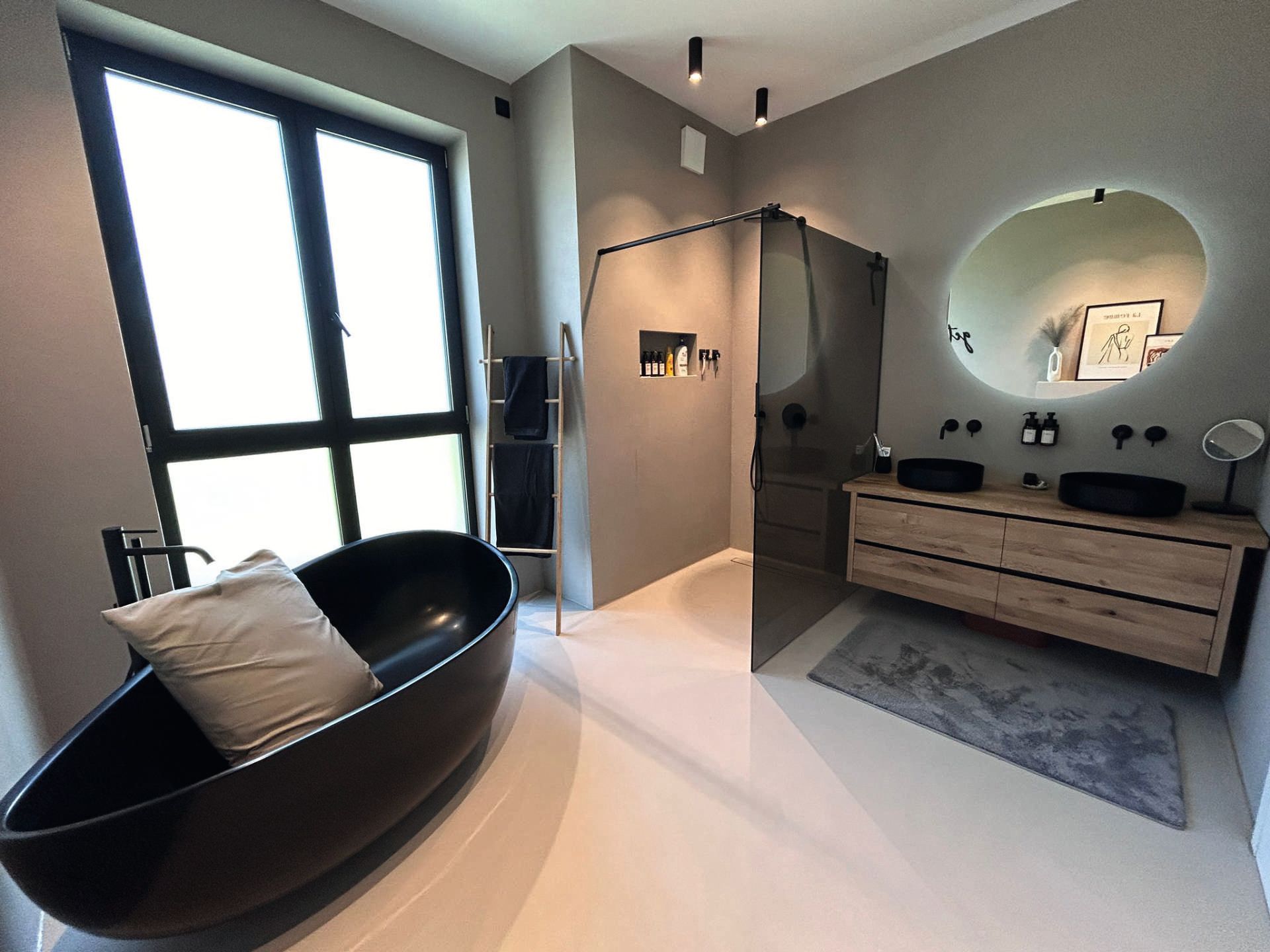 Saniertes, fugenloses Badezimmer mit frei stehender schwarzer Badewanne, ebenerdiger Dusche mit einer getönten Scheibe