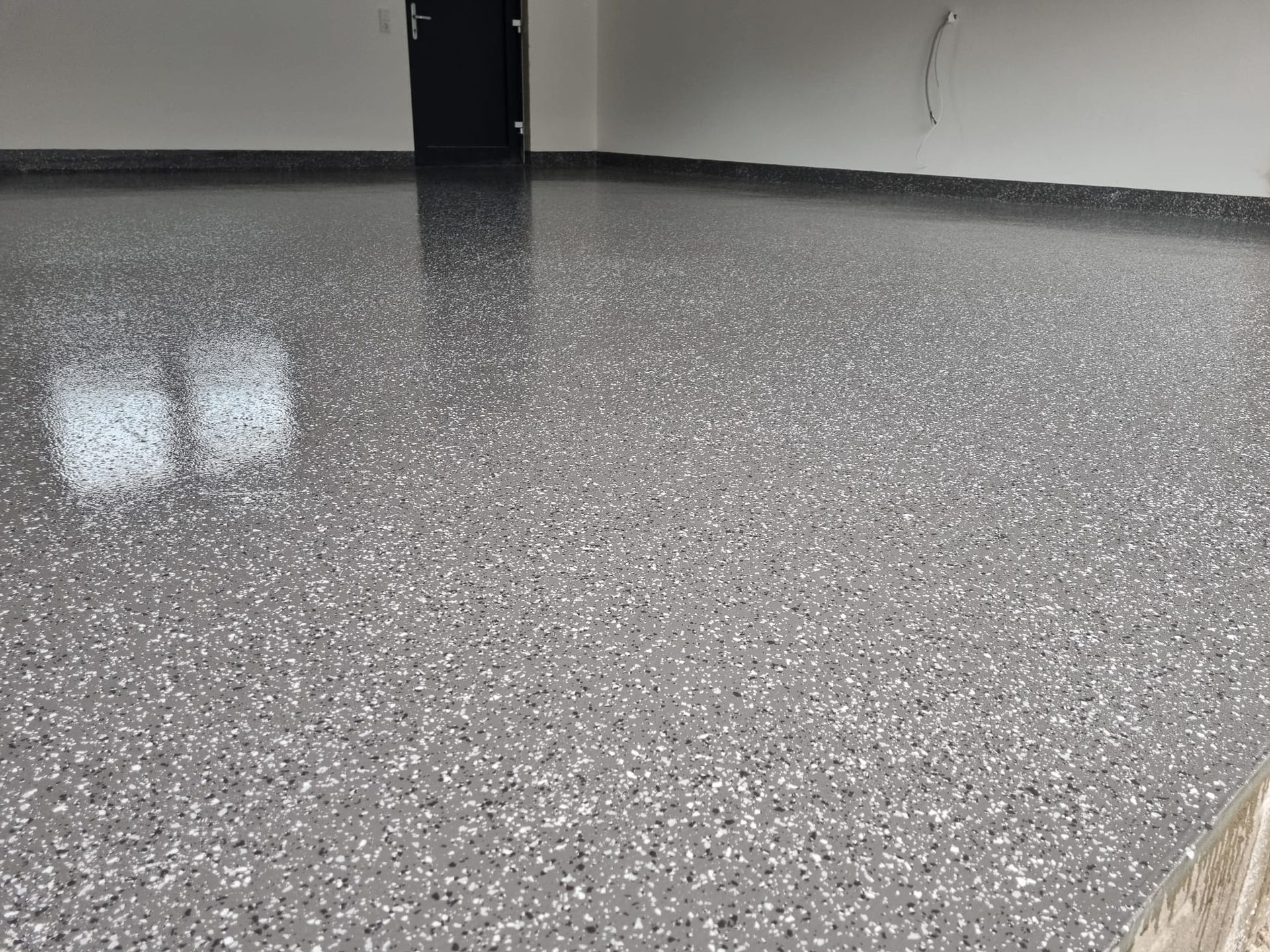 Nahaufnahme eines grau gesprenkelten Bodens mit Spezialbeschichtung in einer Garage