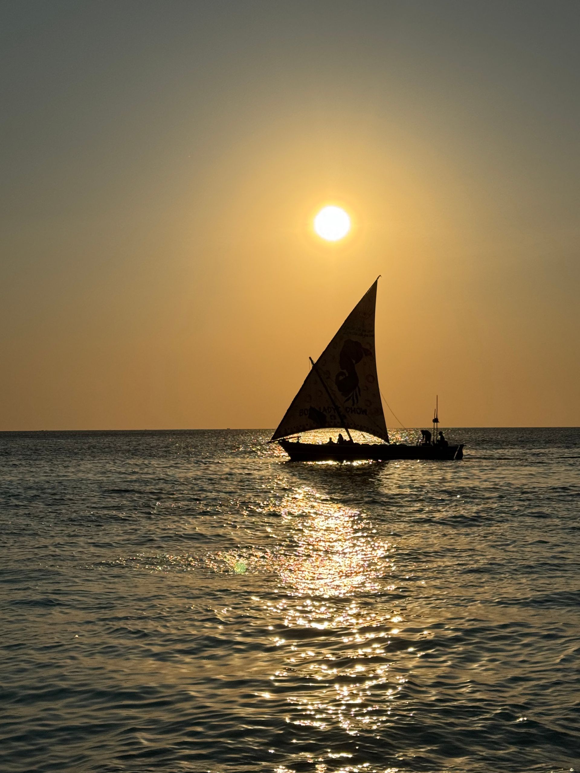 Silueta de un velero sobre el agua con la puesta de sol.