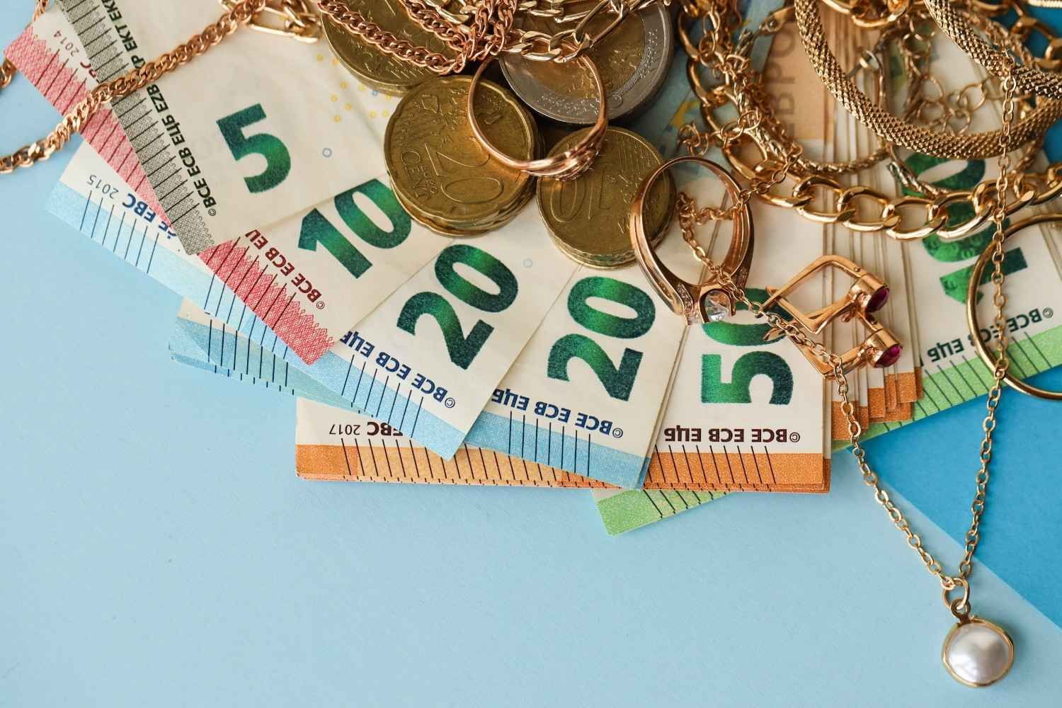 Billetes de euro y joyas de oro sobre un fondo azul claro.