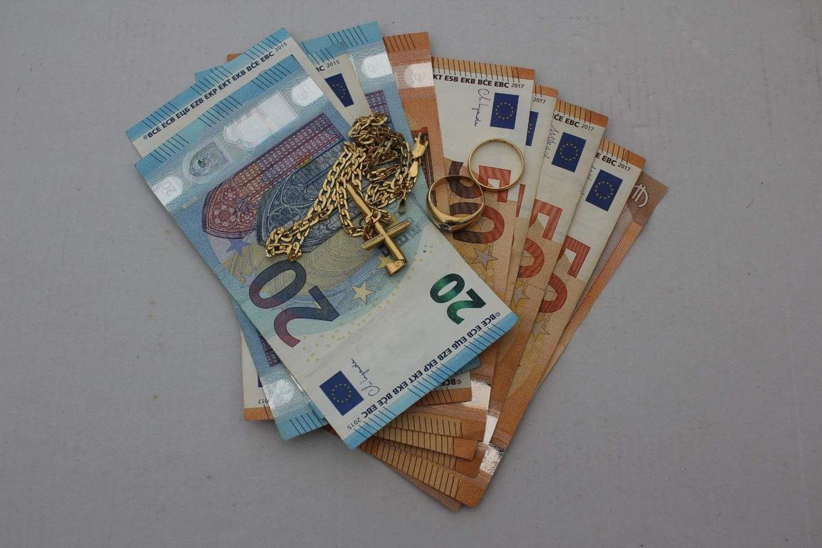 Billetes y monedas de euro esparcidos sobre una superficie gris.