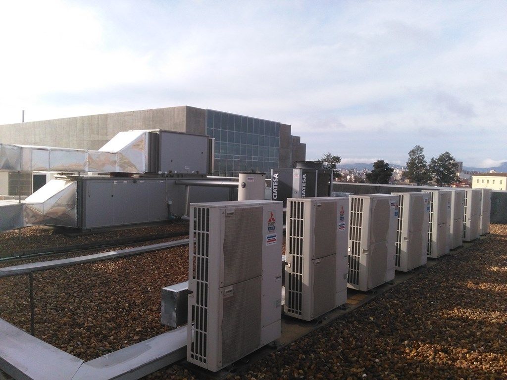 Una fila de aparatos de aire acondicionado están alineados en el techo de un edificio.