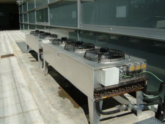 Una fila de acondicionadores de aire de acero inoxidable en el costado de un edificio.