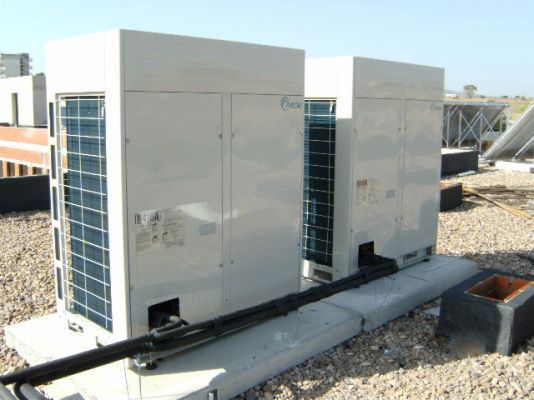 Hay dos aparatos de aire acondicionado en el tejado de un edificio.