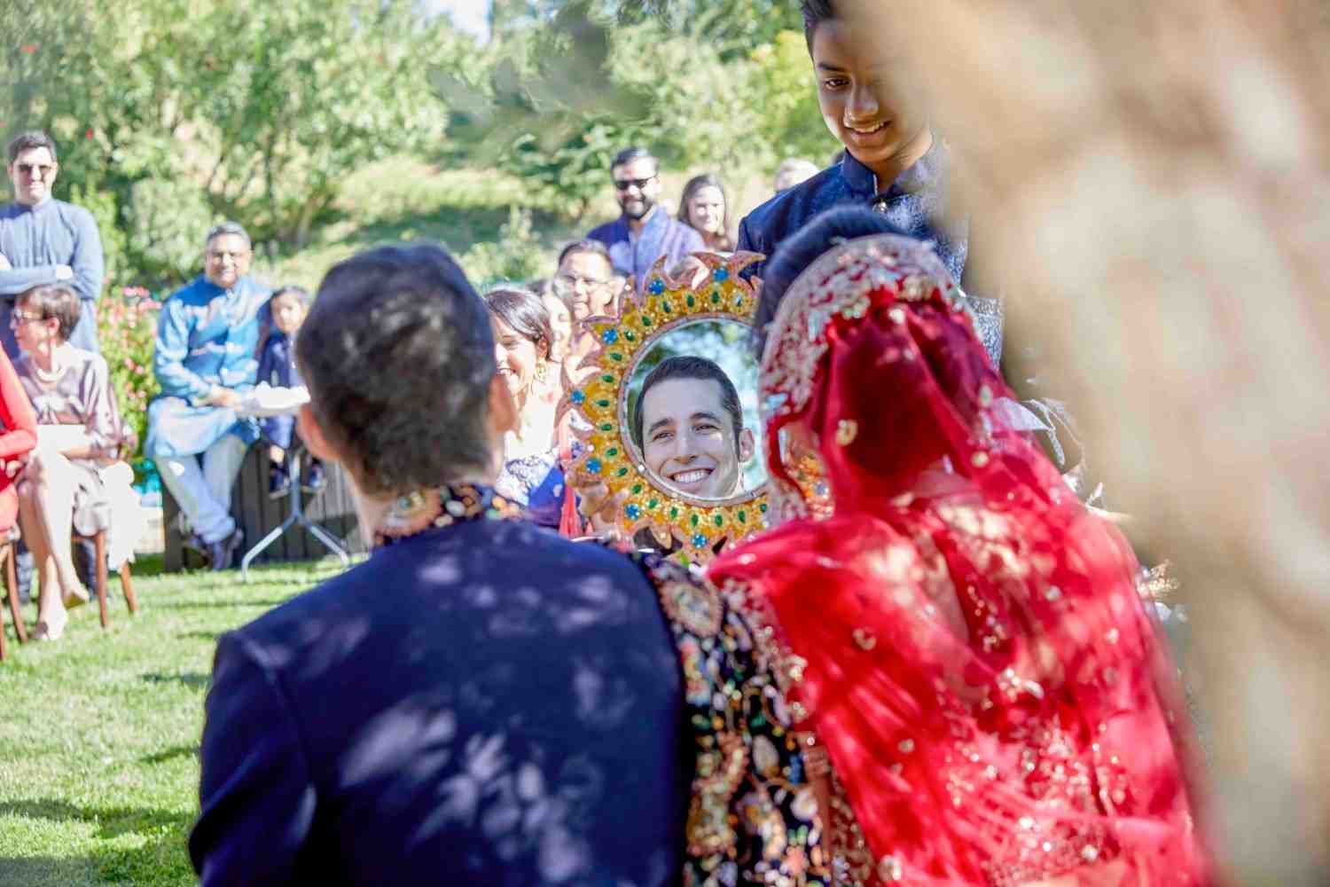Gente al aire libre en una colorida celebración, con un artista vestido de rojo en primer plano.