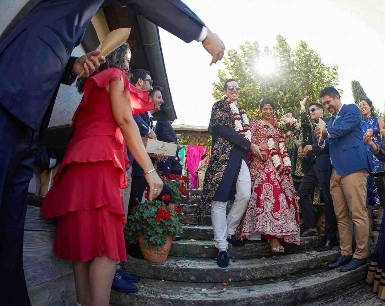 Personas vestidas con ropa formal y colorida de pie en unas escaleras al aire libre durante una celebración.