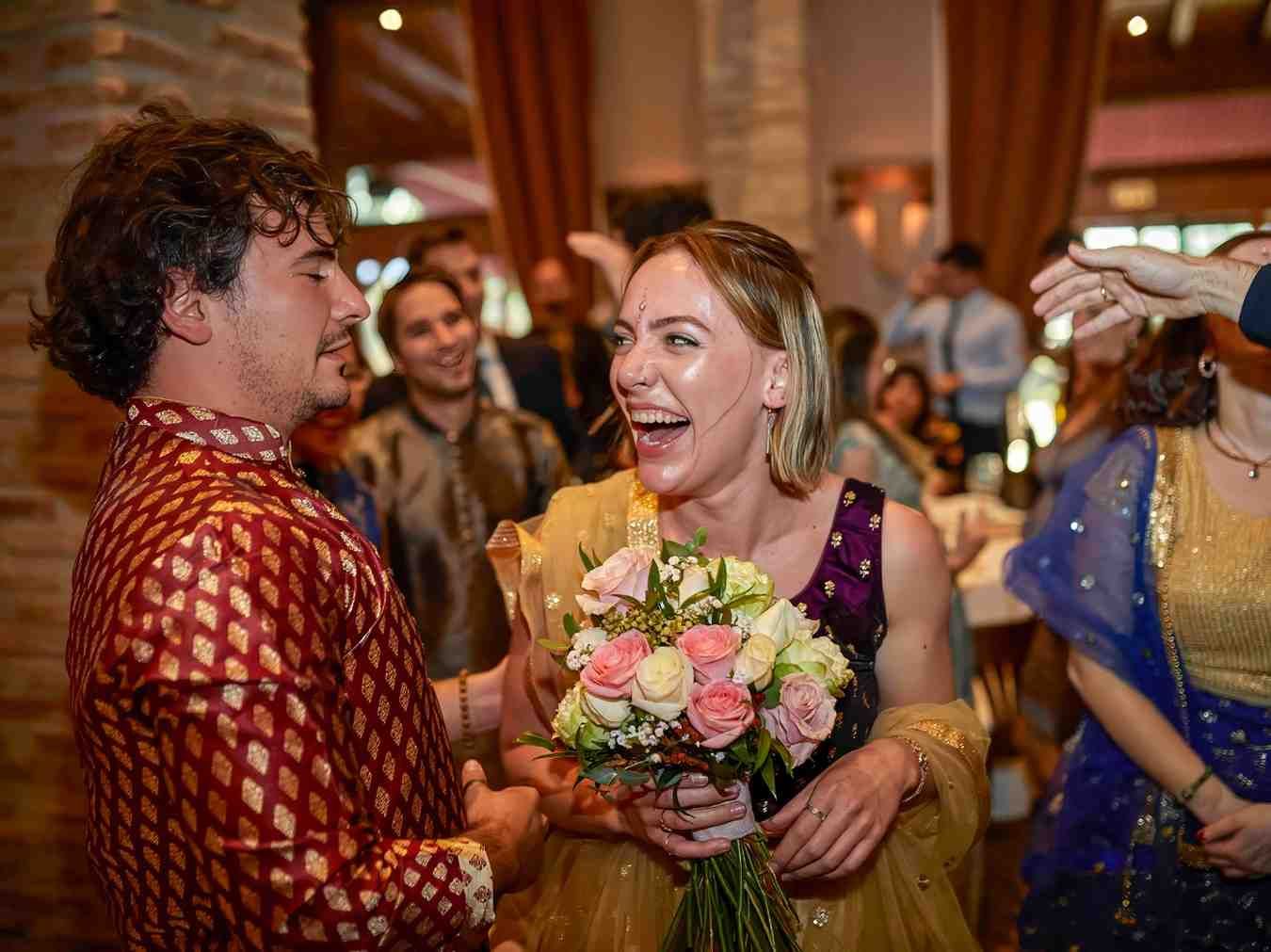 Mujer riendo y sosteniendo un ramo de flores en una celebración festiva en interiores.