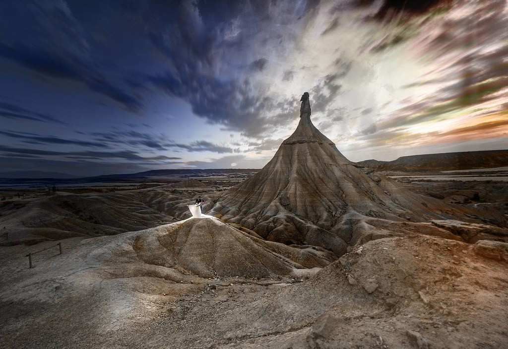 Meseta desértica erosionada bajo un dramático cielo nublado al atardecer.