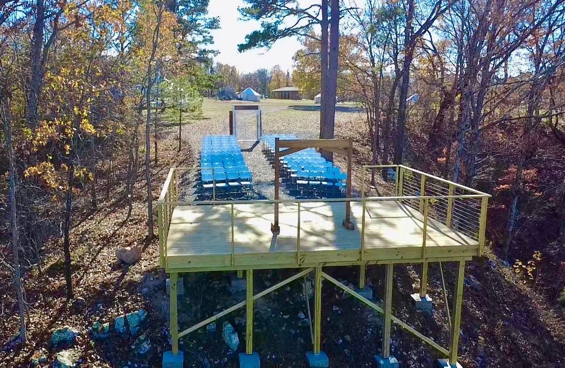Wooden platform with picnic tables, in a wooded area with autumn colors.