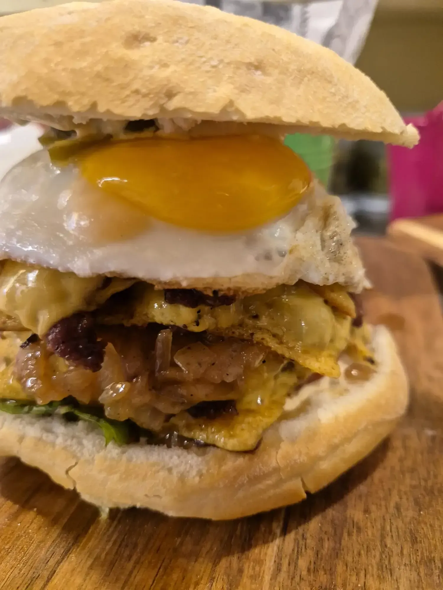 Sándwich con huevo frito, queso y cebolla en un pan.