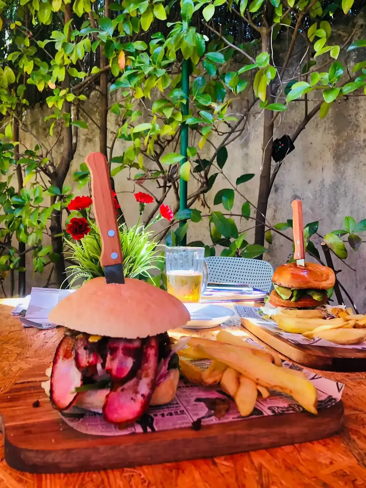 Dos hamburguesas sobre tablas de madera, una ensartada a cuchillo