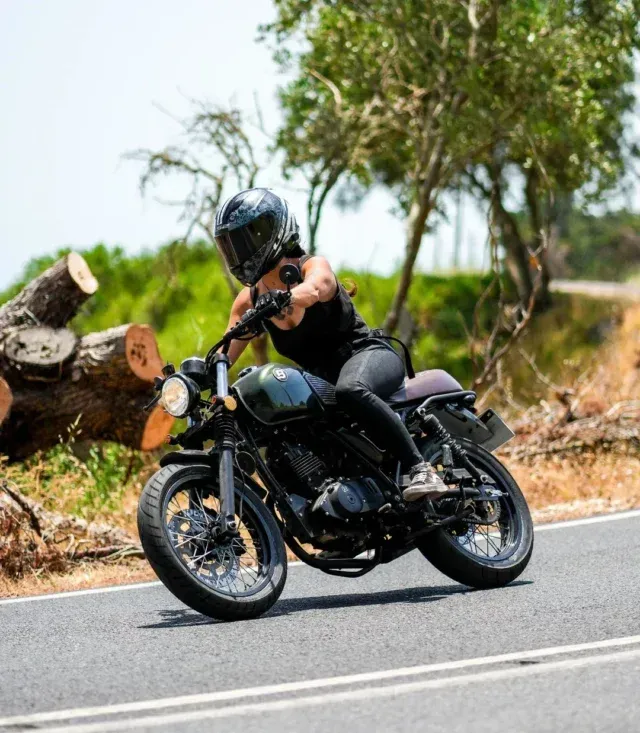 Eine Frau fährt mit einem Motorrad eine Straße entlang.