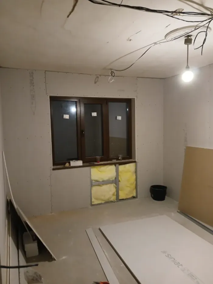 Techo en construcción, con estructura de metal expuesta, cableado y paneles de yeso parcialmente instalados.