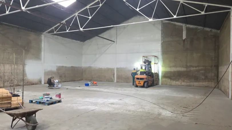 Amoladora angular con disco de corte, junto a una pila de baldosas en una caja de cartón.