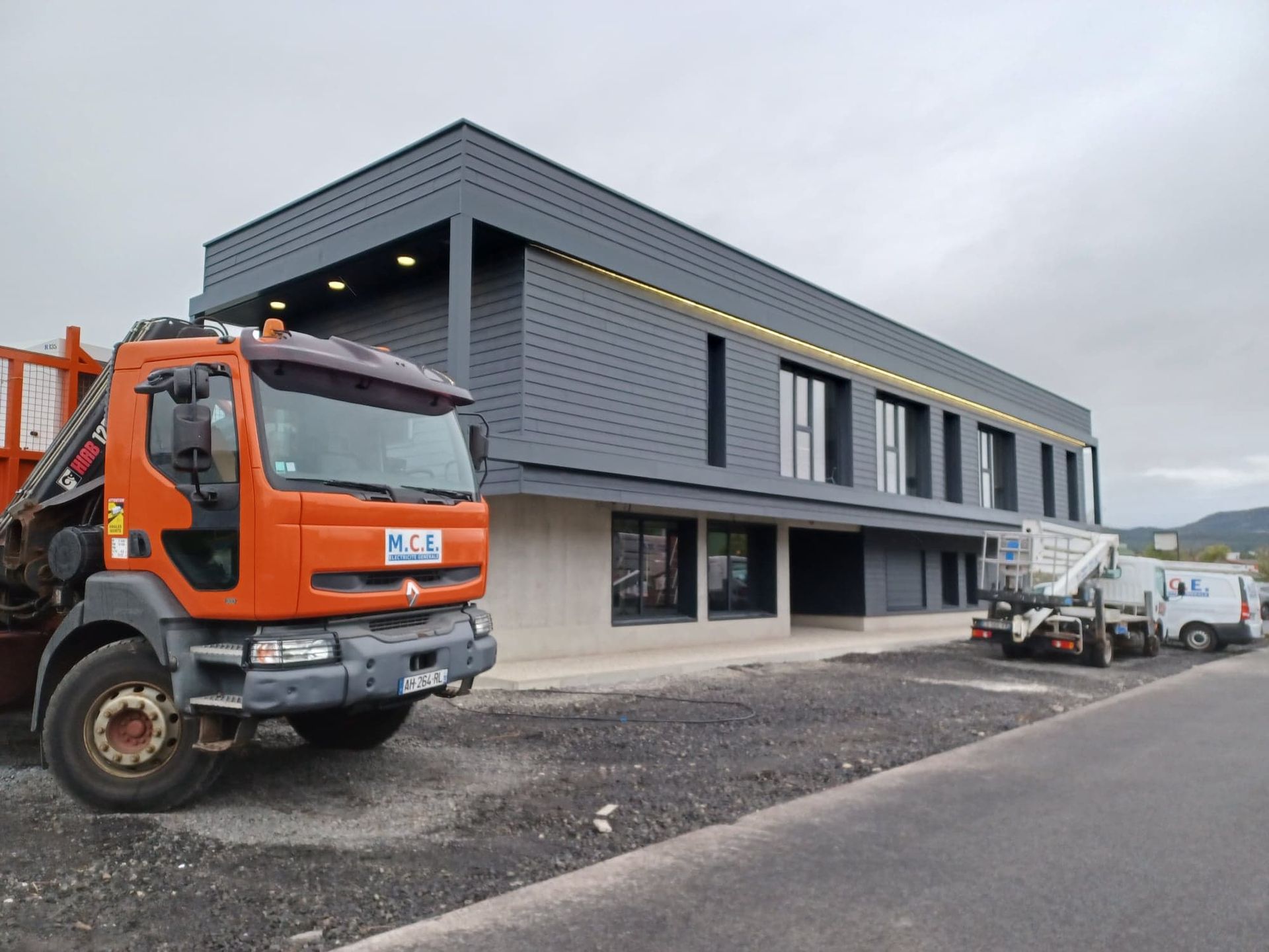 Un camion orange devant un bâtiment gris