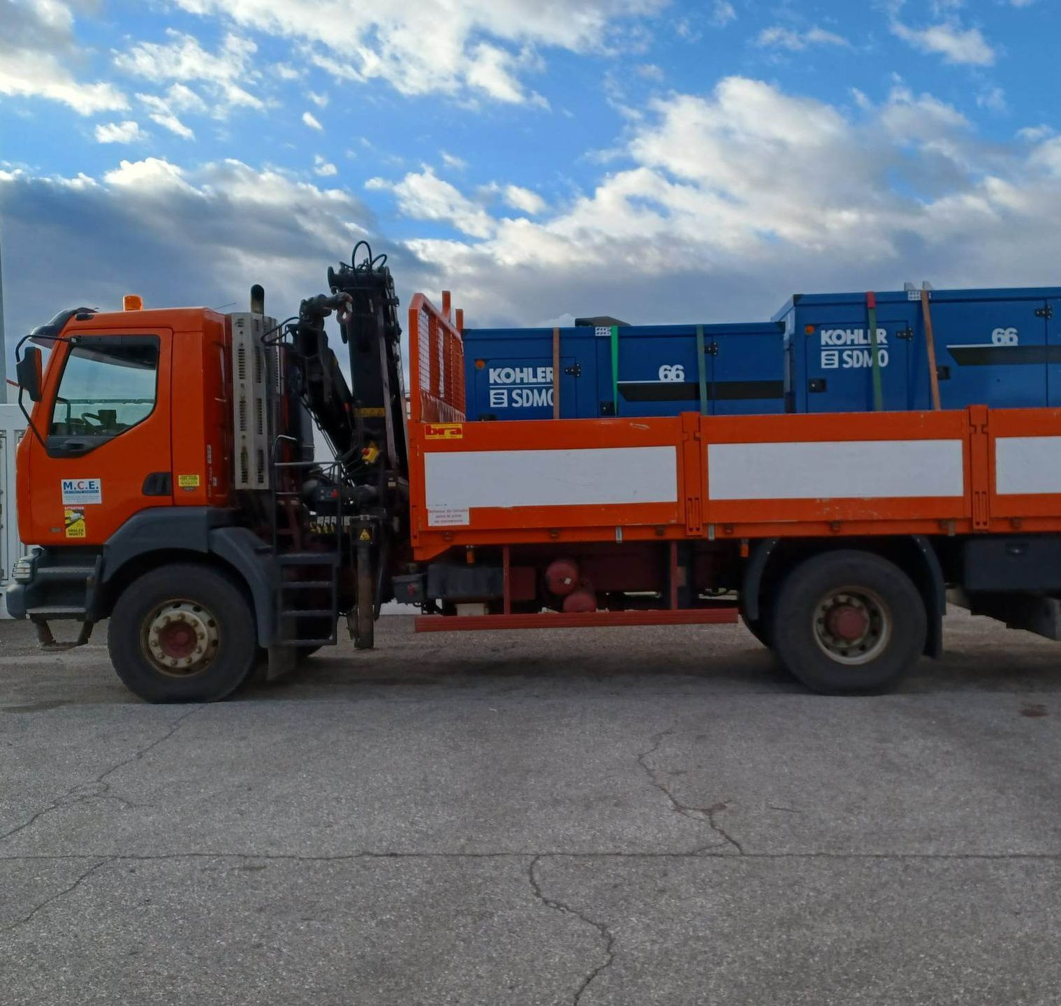 Un camion orange qui transporte des groupes électrogène