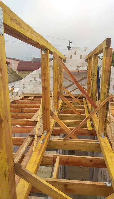 Charpente de toit en bois en construction, avec poutres et entretoises de soutien.