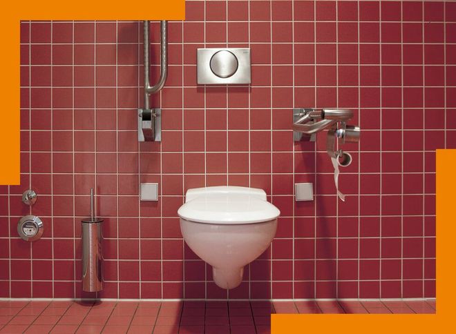 Toilettes carrelées de rouge, avec une cuvette blanche et des équipements chromés, centrées sous une plaque de chasse d’eau