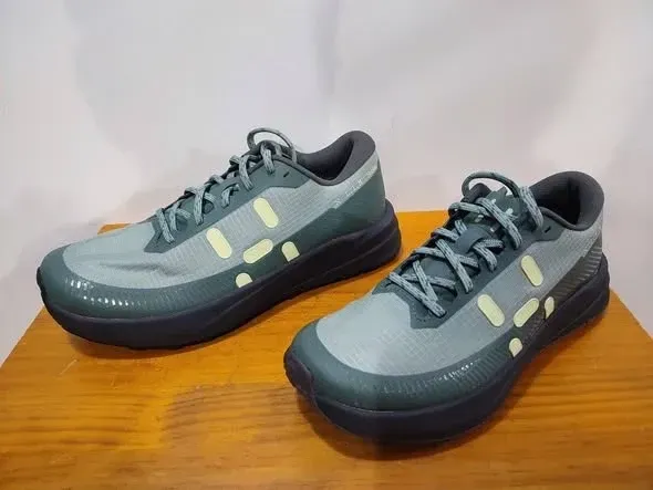 Un par de zapatillas deportivas grises con suelas negras sobre una superficie de madera.