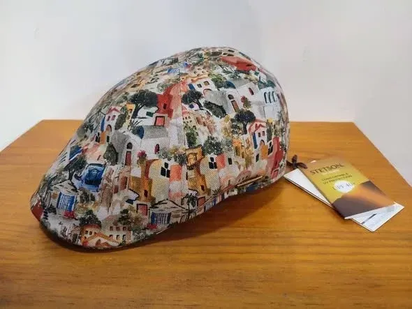 Gorra plana multicolor de retazos sobre una mesa de madera con una etiqueta adjunta.