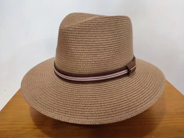 Sombrero de paja tejida de color tostado con una banda marrón oscuro sobre una superficie de madera.