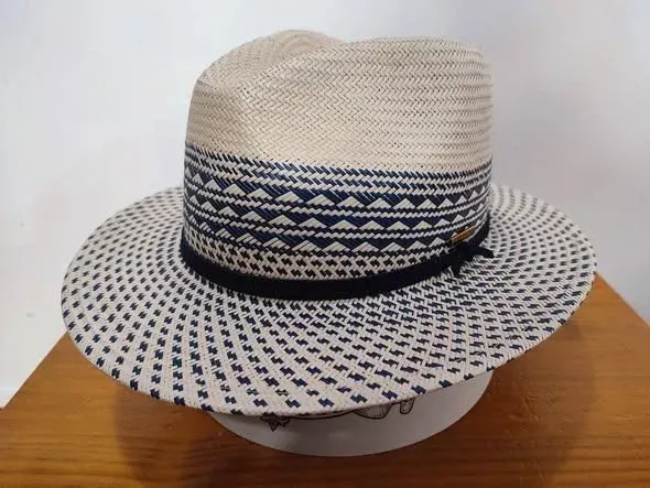 Sombrero fedora de paja con banda y ala estampadas en azul marino, sobre una superficie blanca.