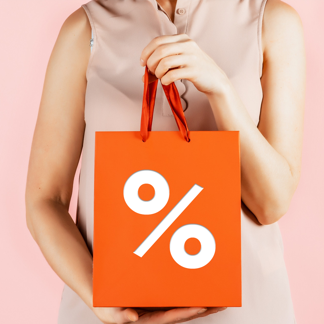 Donna che tiene in mano una borsa della spesa arancione con il simbolo percentuale bianco.
