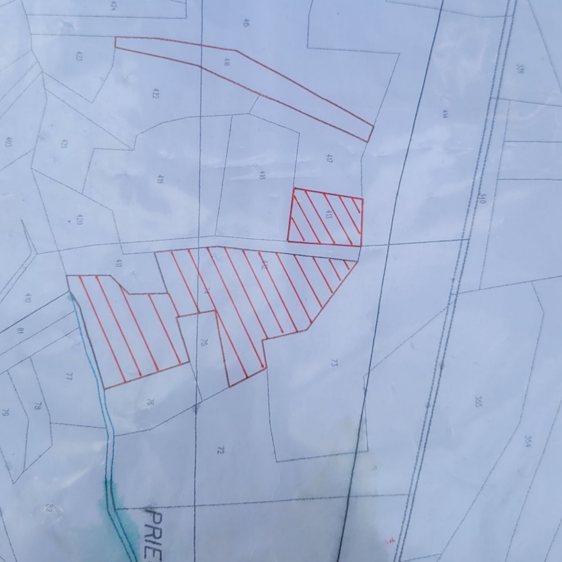 Plan cadastral avec zones de propriété hachurées en rouge et parcelles délimitées sur fond clair.
