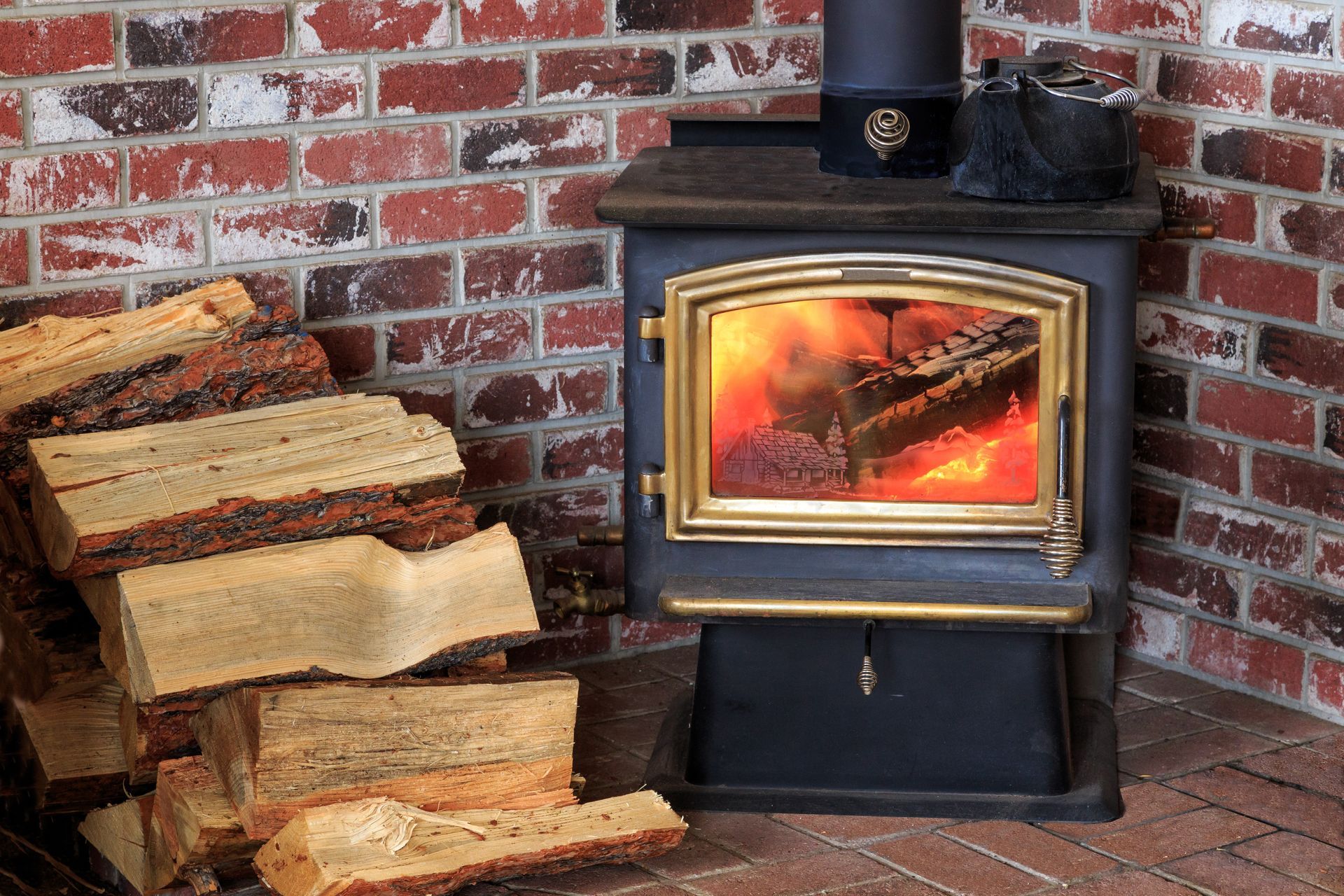 Poêle à bois avec un feu crépitant à côté d'une pile de bois de chauffage contre un mur de briques.