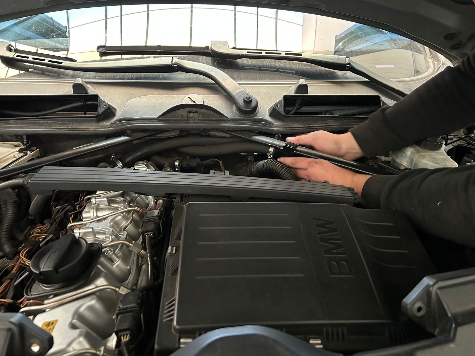 Mécanicien en salopette rouge utilisant une clé sur un moteur de voiture.