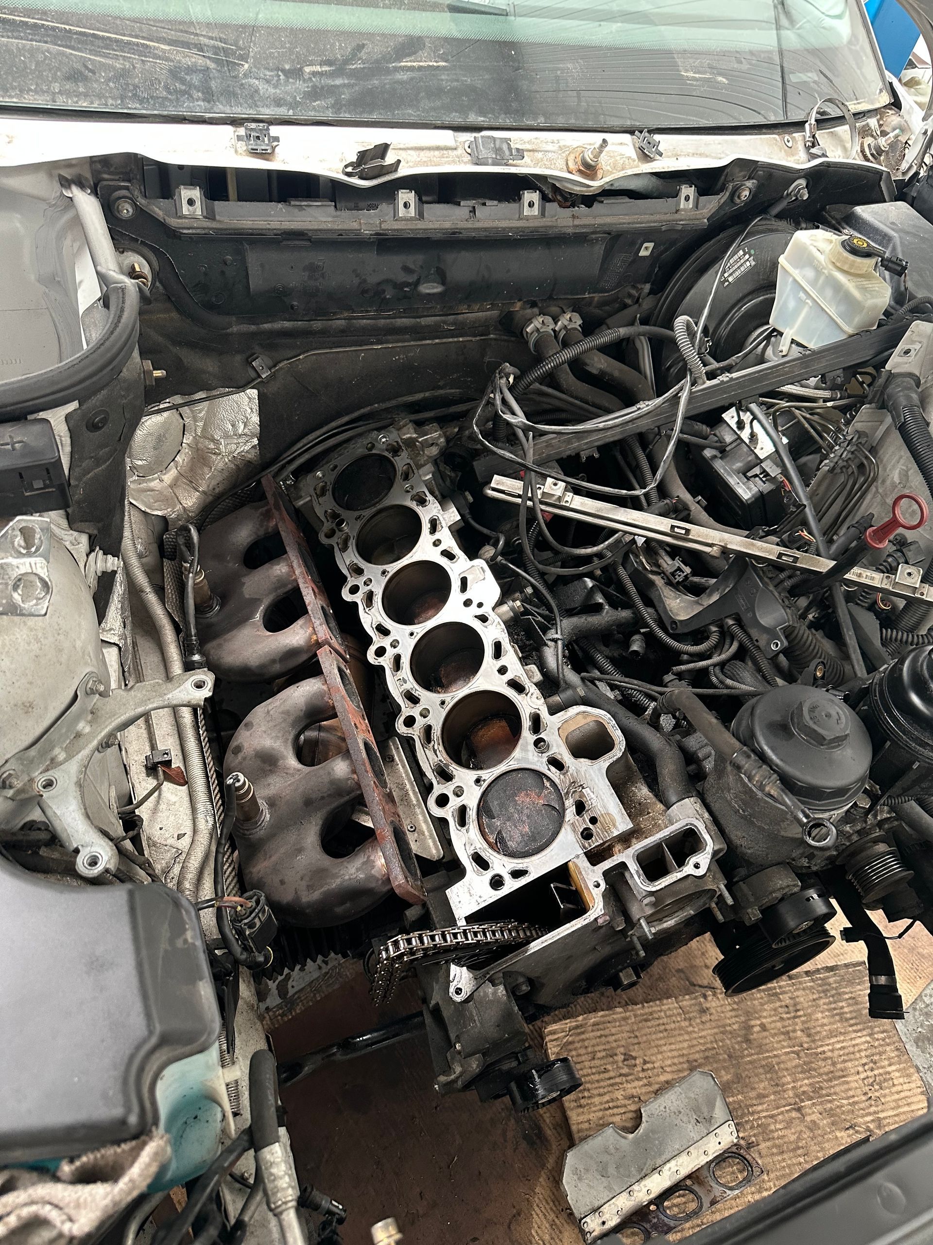 Assemblage du moteur sur une palette en bois, entouré de tuyaux et de tubes.