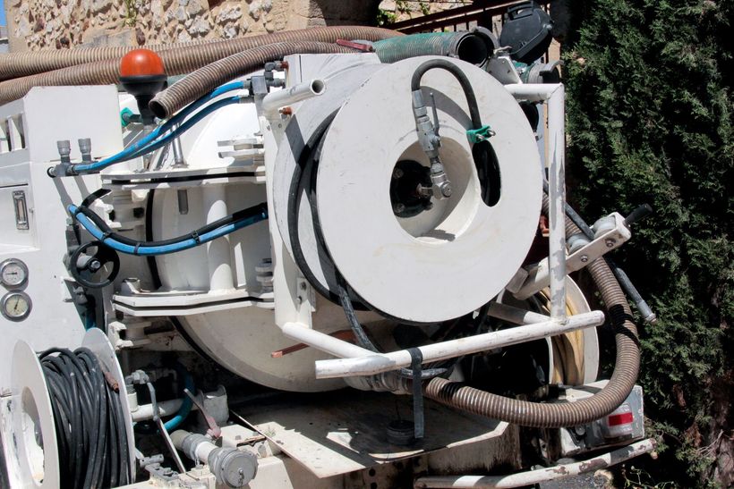 Machine industrielle blanche avec tuyaux et une grande ouverture circulaire dans un environnement extérieur.