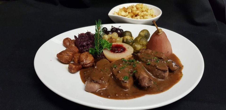 Une assiette blanche garnie de viande et de légumes sur une table.