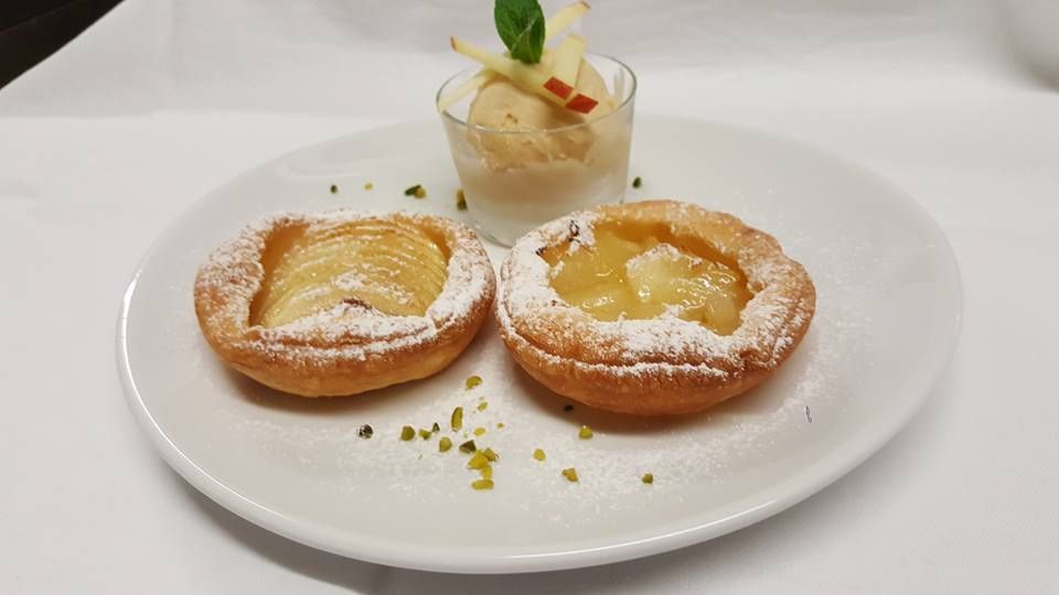 Une assiette blanche surmontée de deux pâtisseries et d'une coupe de glace.