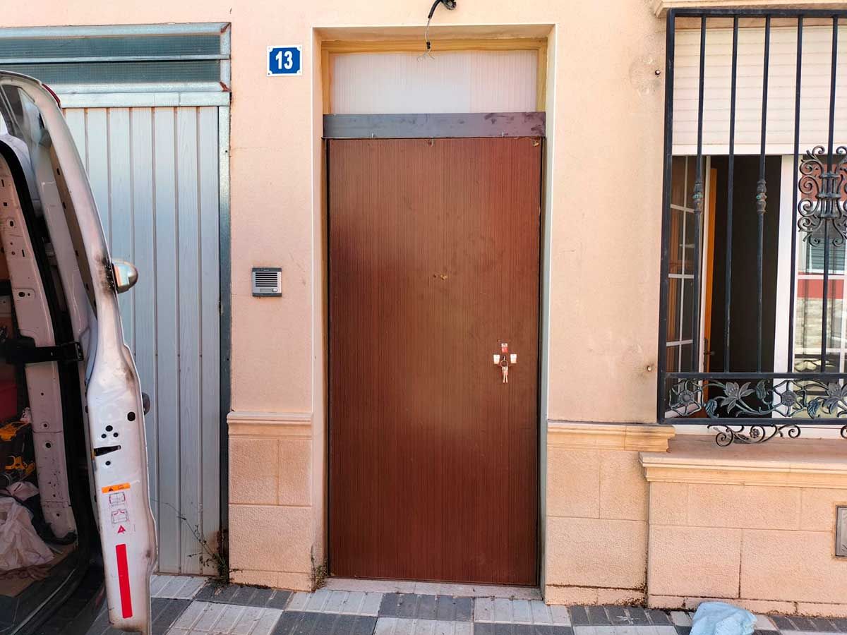 Una furgoneta blanca está estacionada frente a una puerta con el número 13.