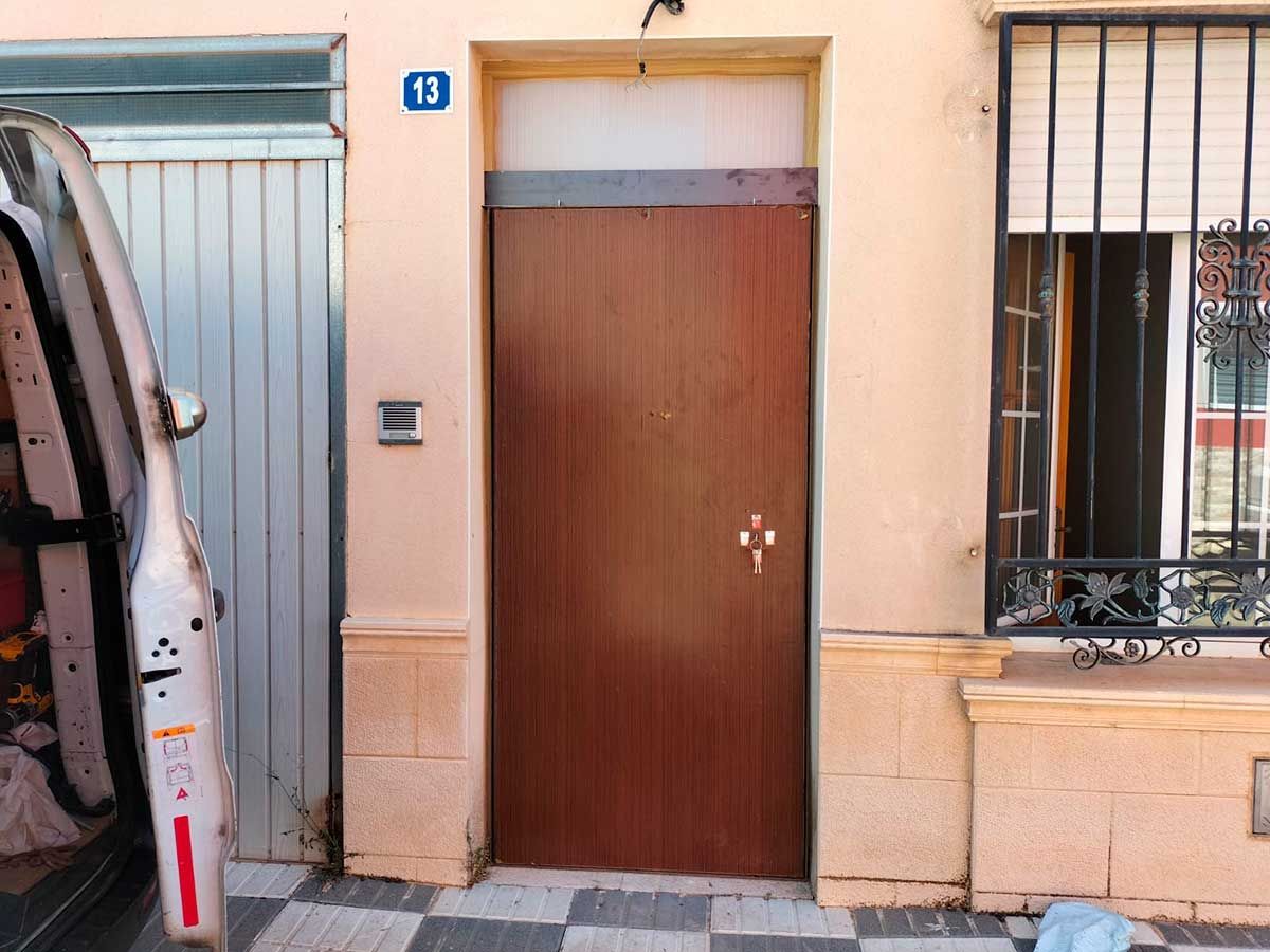 Una furgoneta blanca está estacionada frente a una puerta con el número 13.