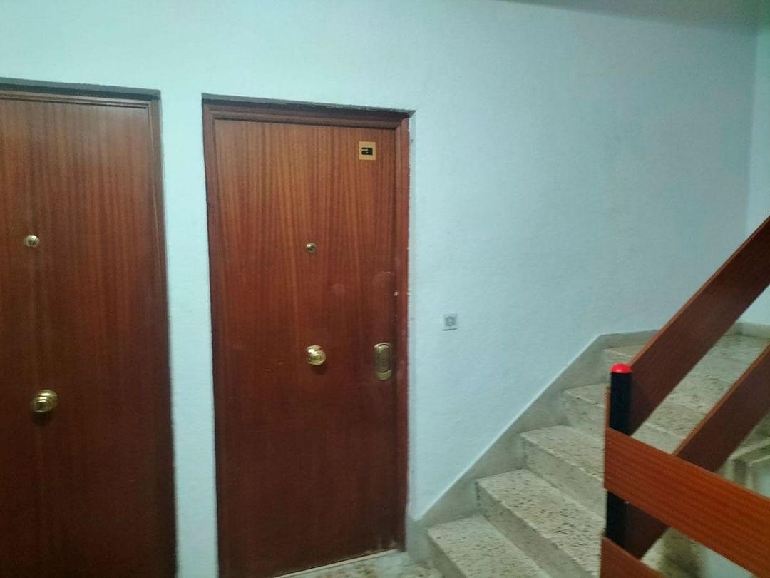 Un pasillo con escaleras y una puerta de madera.