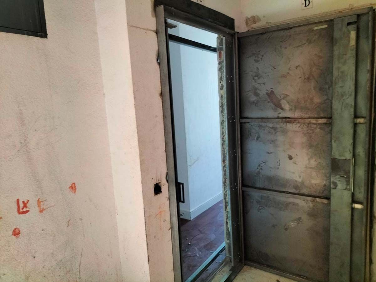 Una puerta de metal está abierta a una habitación de un edificio.