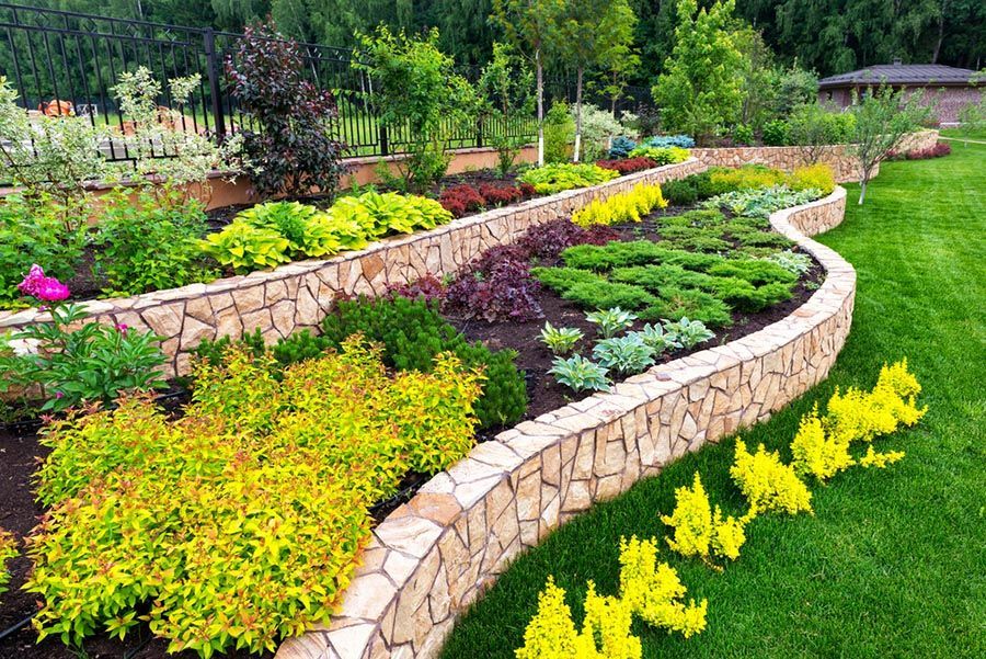 Jardins en pierre aux formes sinueuses, ornés de fleurs colorées et d'arbustes verdoyants, dans un parc paysager