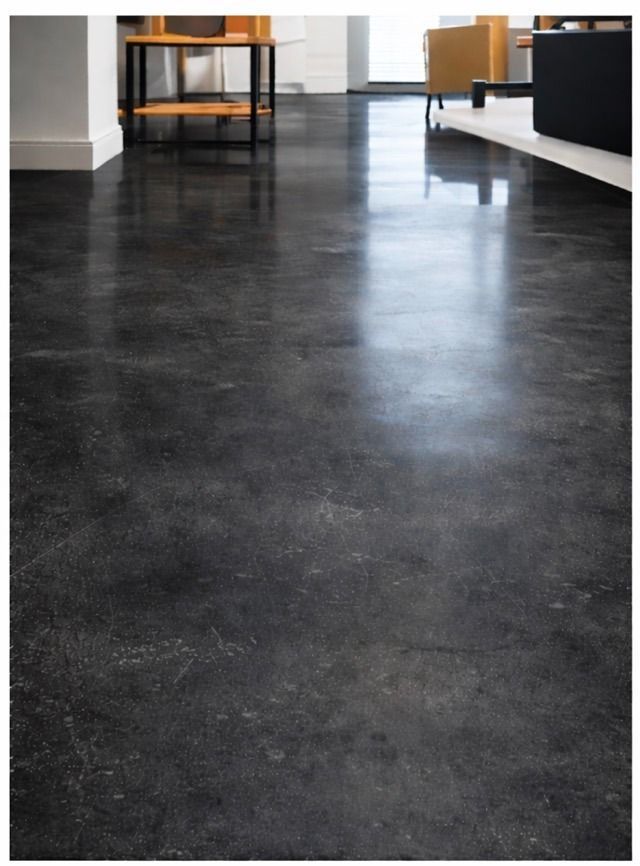 Suelo de hormigón oscuro y pulido en una habitación. Reflejos y sutiles variaciones de color.