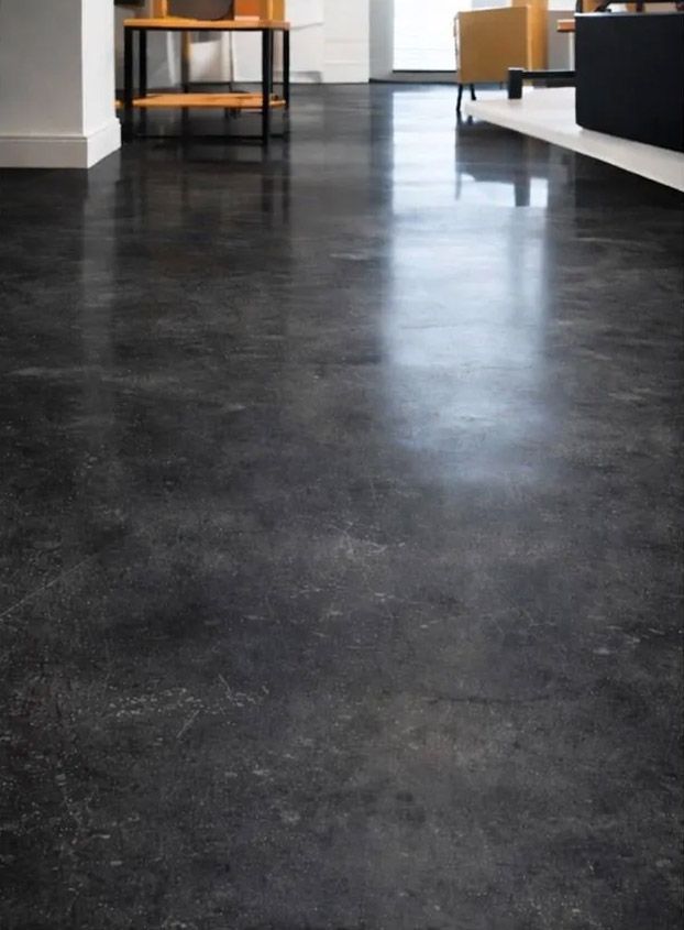 Suelo de hormigón oscuro y pulido en una habitación. Reflejos y sutiles variaciones de color.
